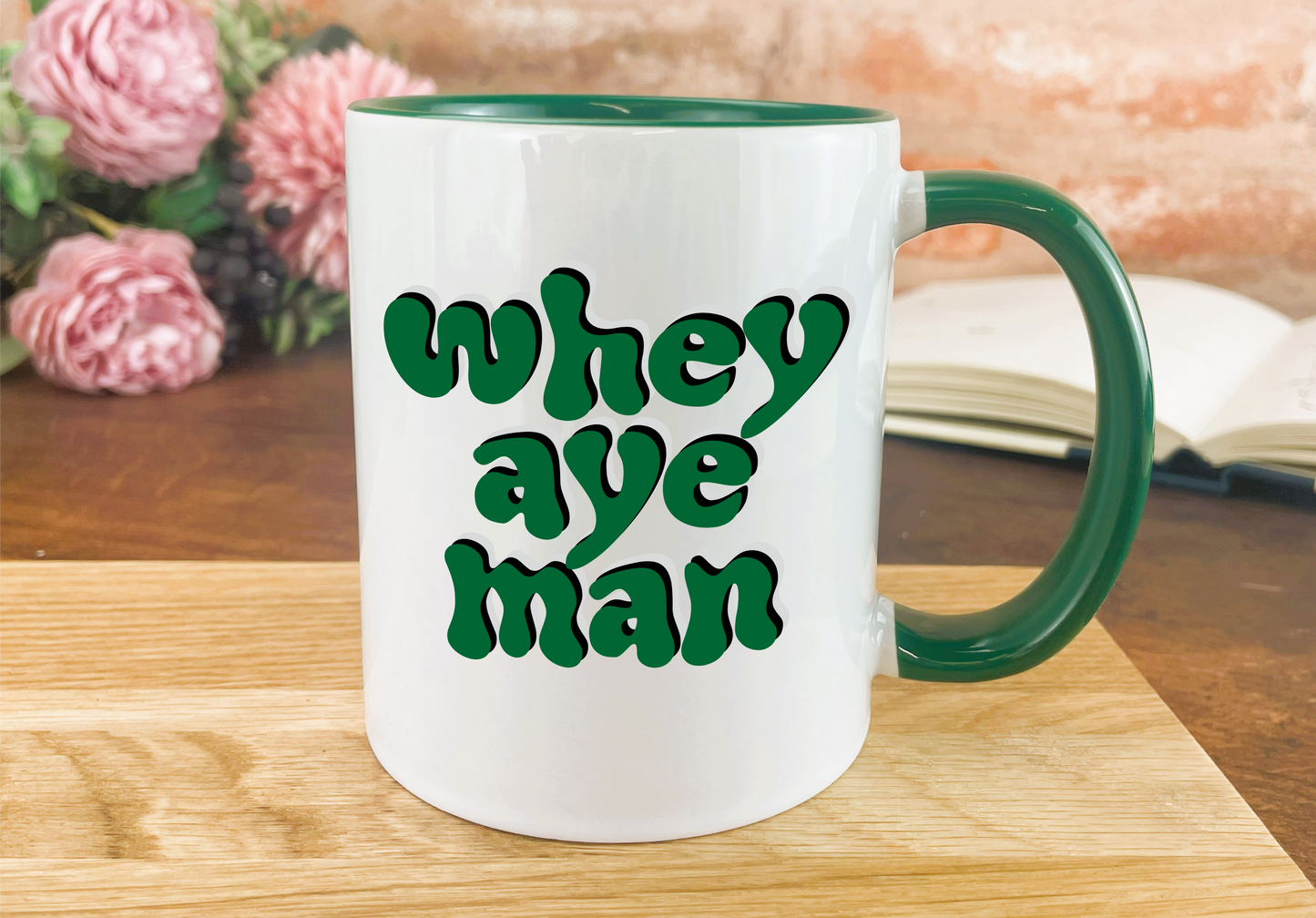 a green and white coffee mug sitting on a wooden table