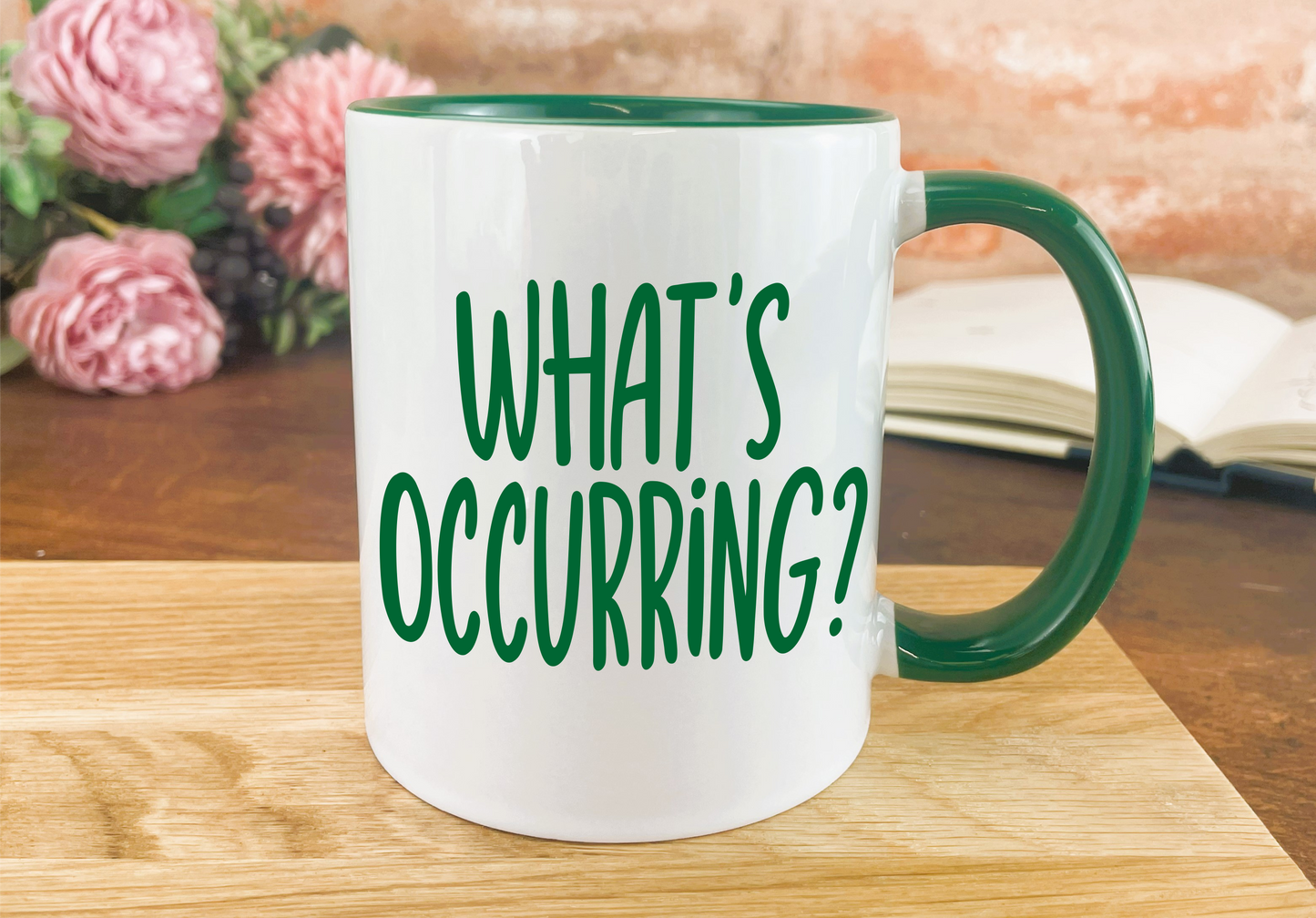 a green and white coffee mug sitting on top of a wooden table