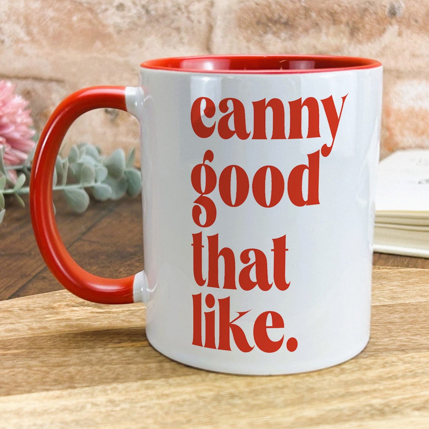a red and white coffee mug sitting on top of a wooden table