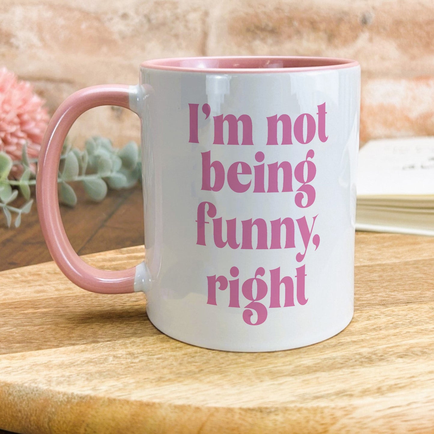 a pink and white coffee mug sitting on top of a wooden table