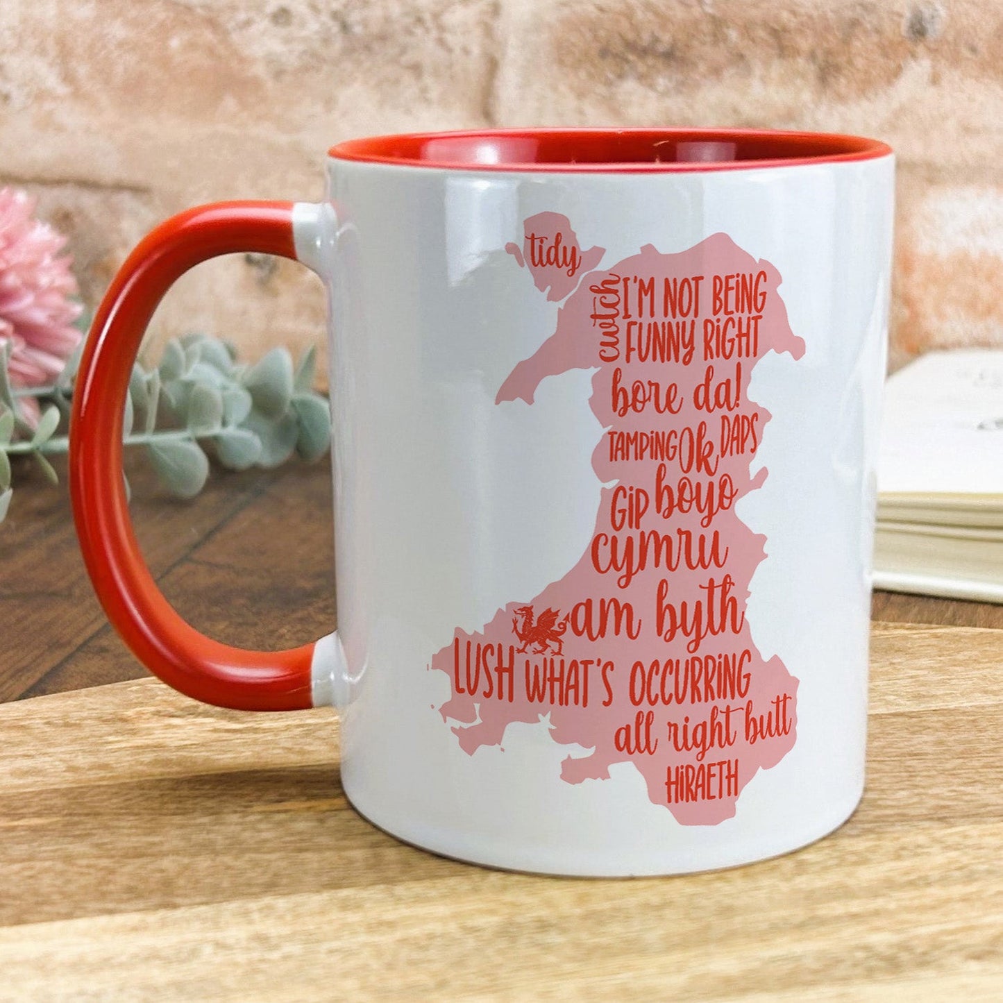 a red and white mug sitting on top of a wooden table