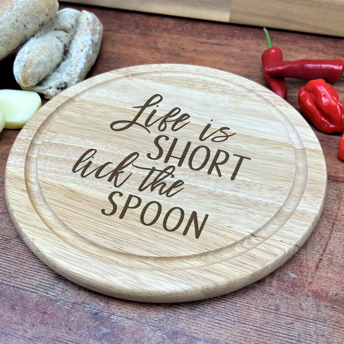 a wooden cutting board with the words life is short but the spoon on it