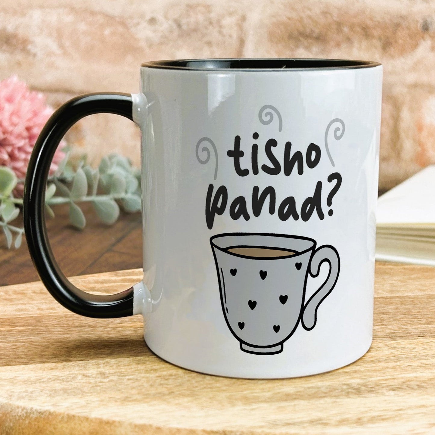a black and white coffee mug sitting on top of a wooden table