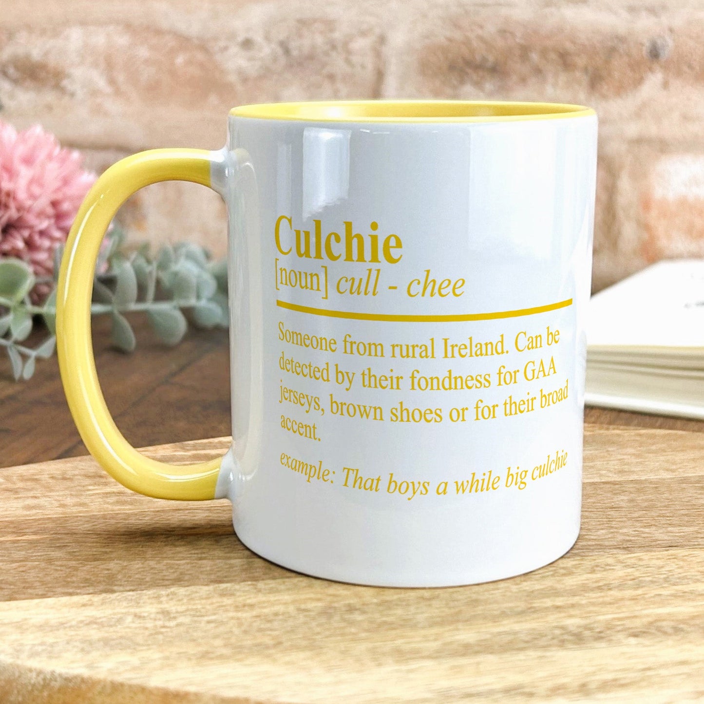 a yellow and white coffee mug sitting on top of a wooden table