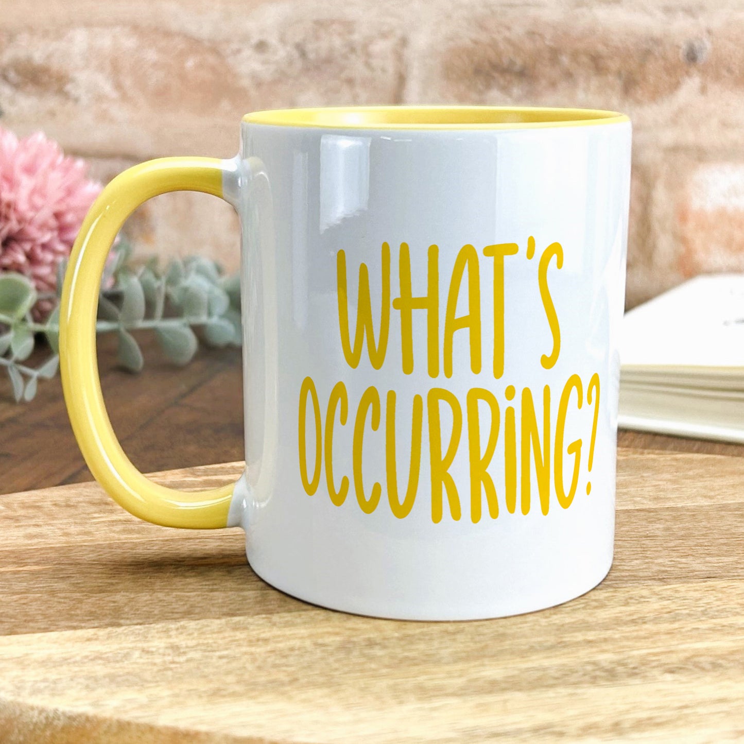 a yellow and white coffee mug sitting on top of a wooden table