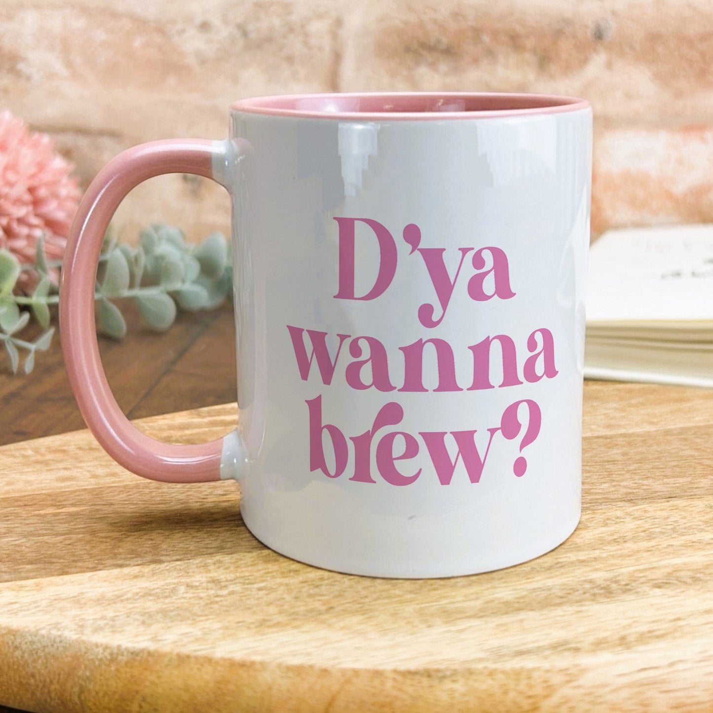 a pink and white coffee mug sitting on top of a wooden table