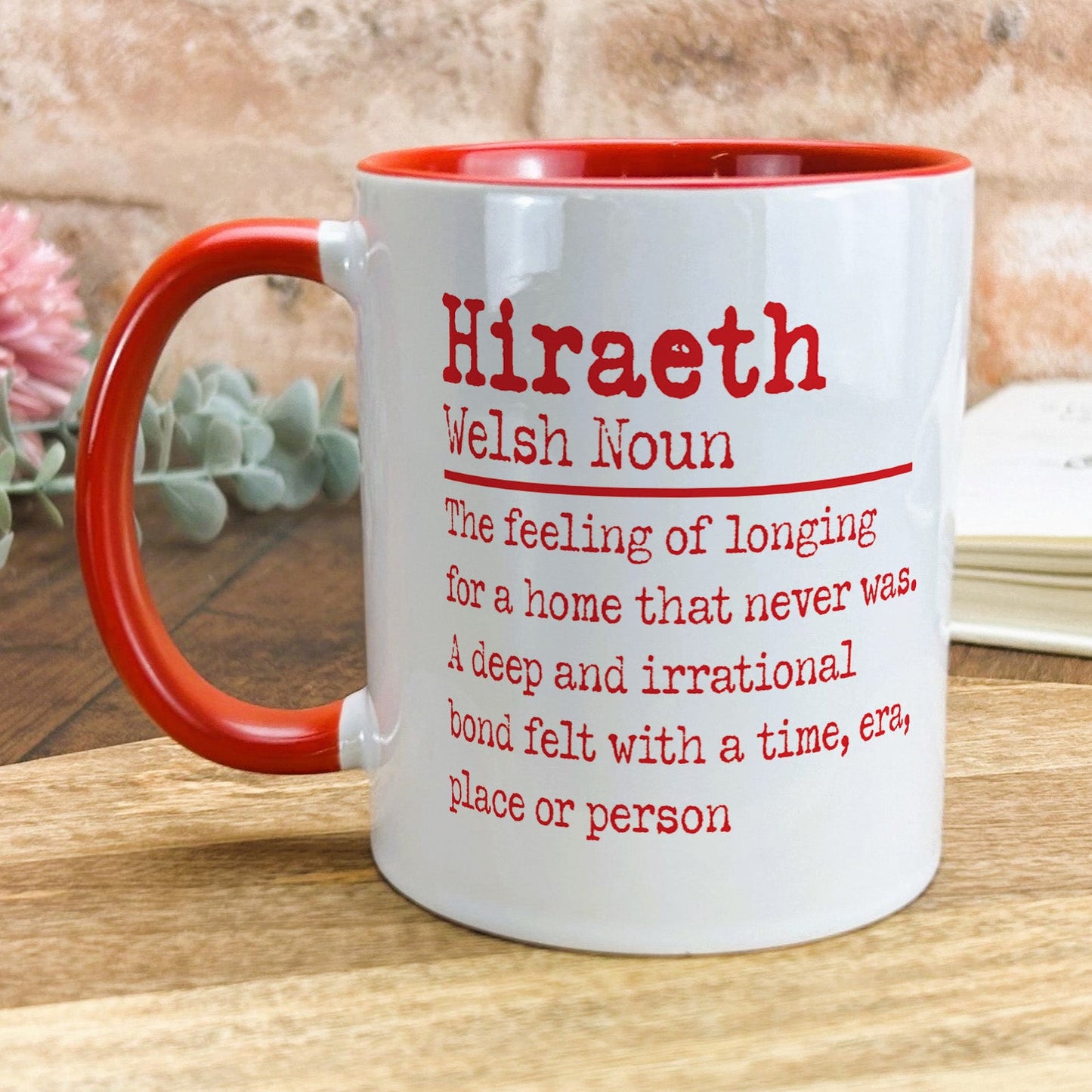 a red and white coffee mug sitting on top of a wooden table