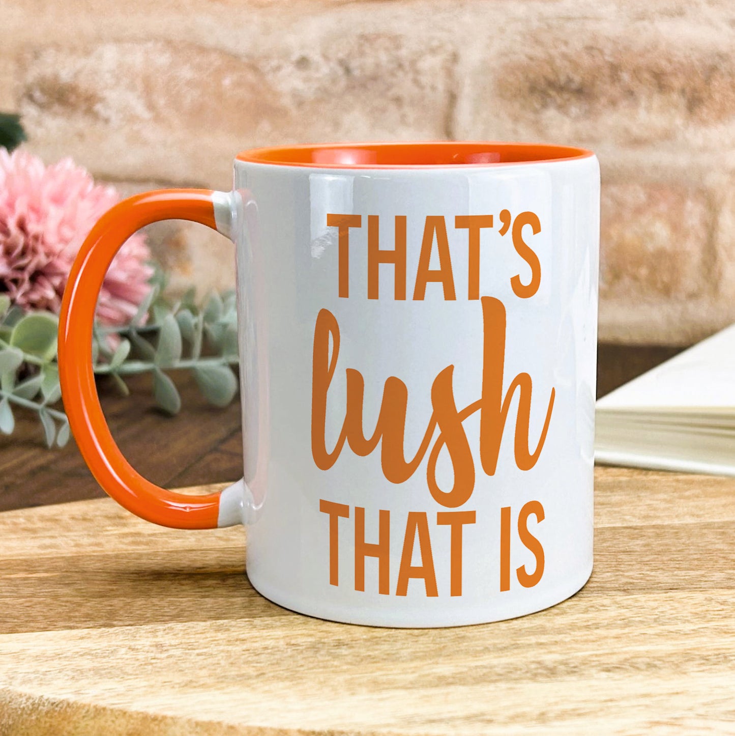 a white and orange coffee mug sitting on top of a wooden table