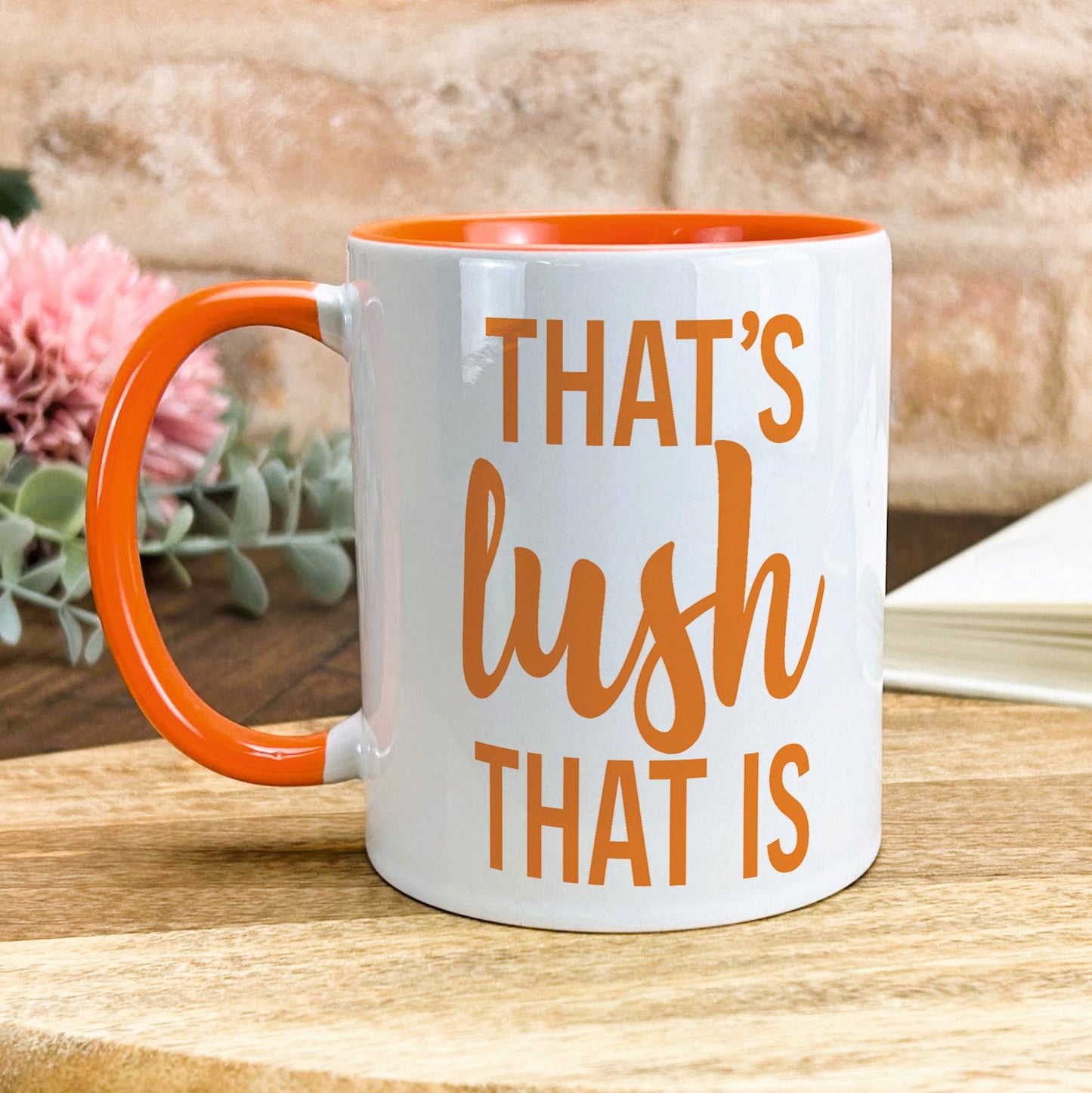 a white and orange coffee mug sitting on top of a wooden table