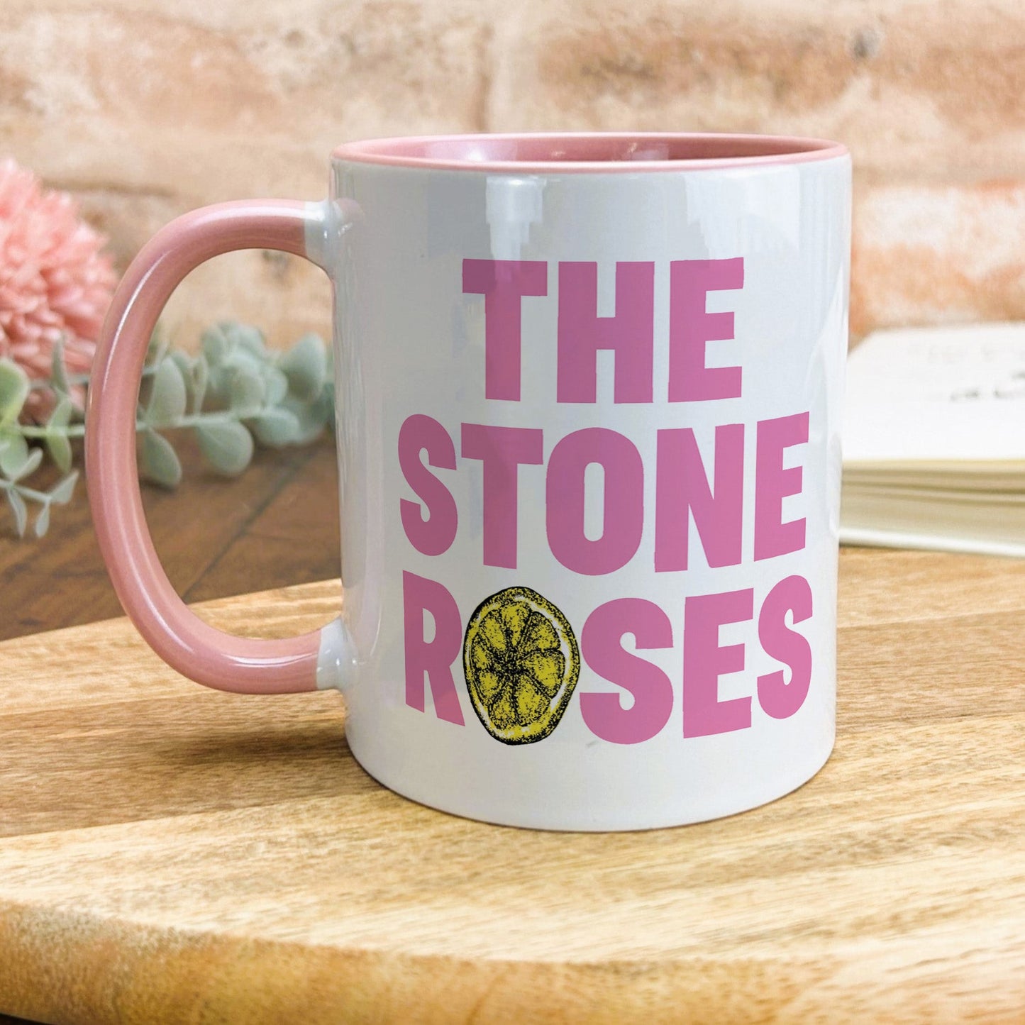 a pink and white coffee mug sitting on top of a wooden table