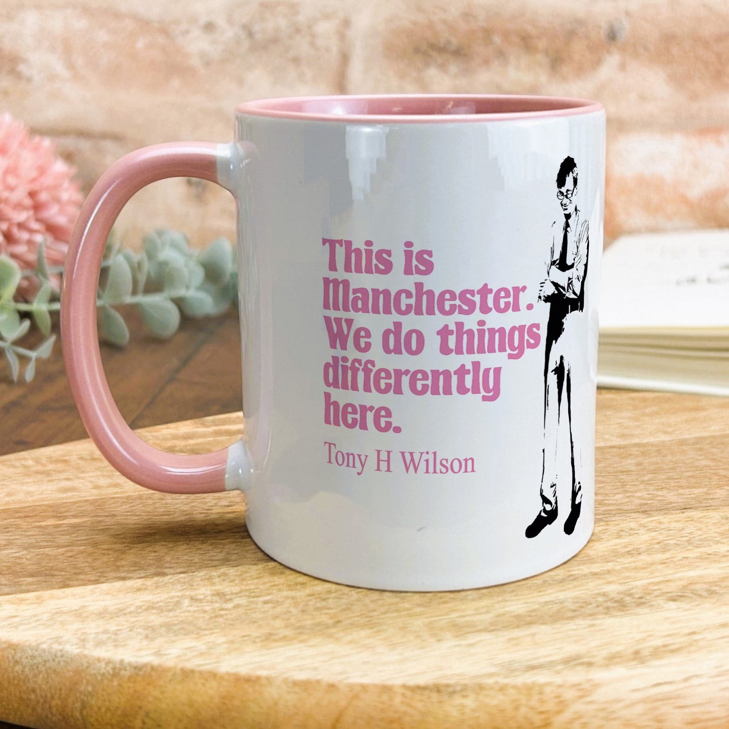 a pink and white coffee mug sitting on top of a wooden table