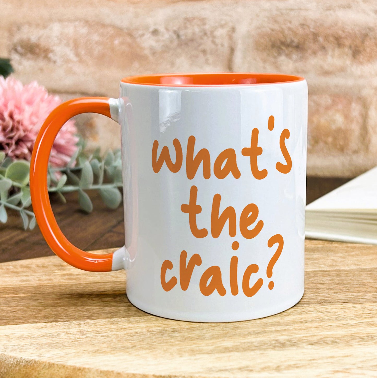 a white and orange coffee mug sitting on top of a wooden table