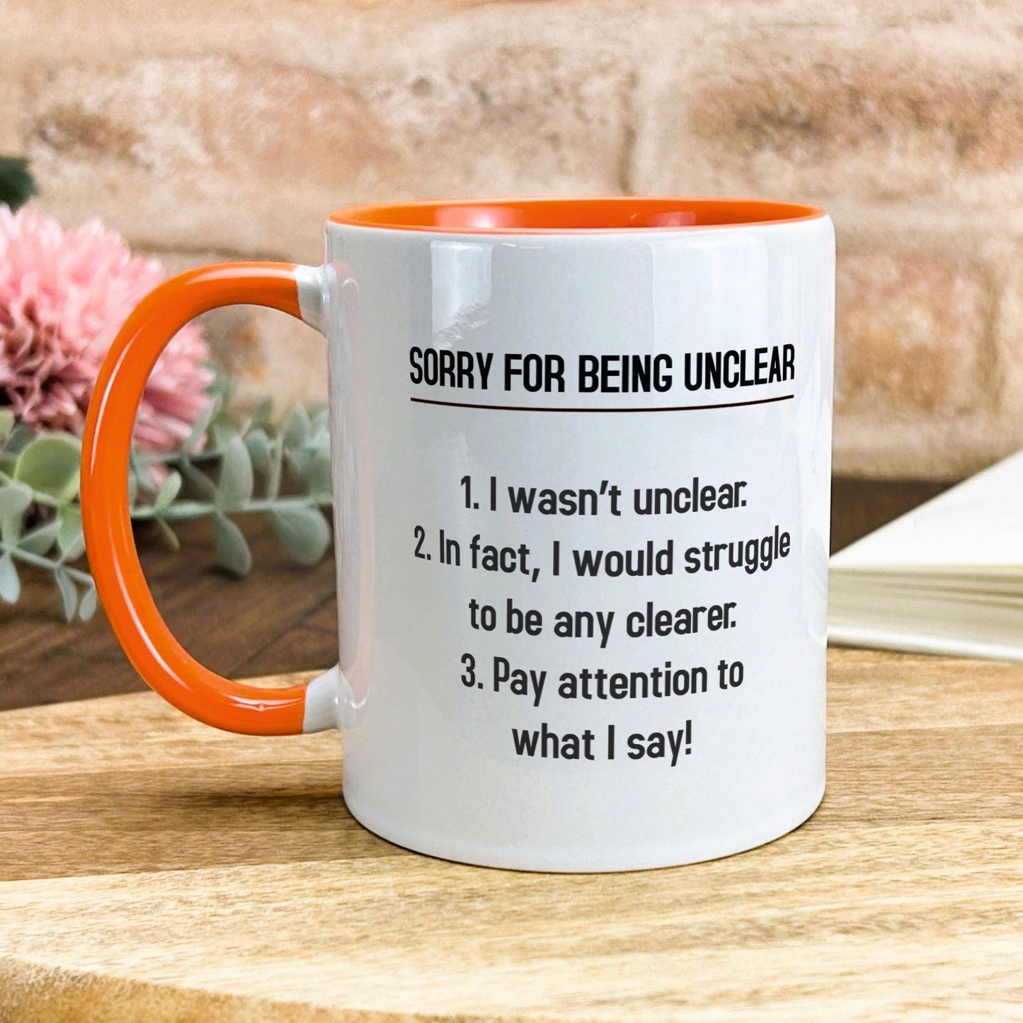 a white and orange coffee mug sitting on top of a wooden table