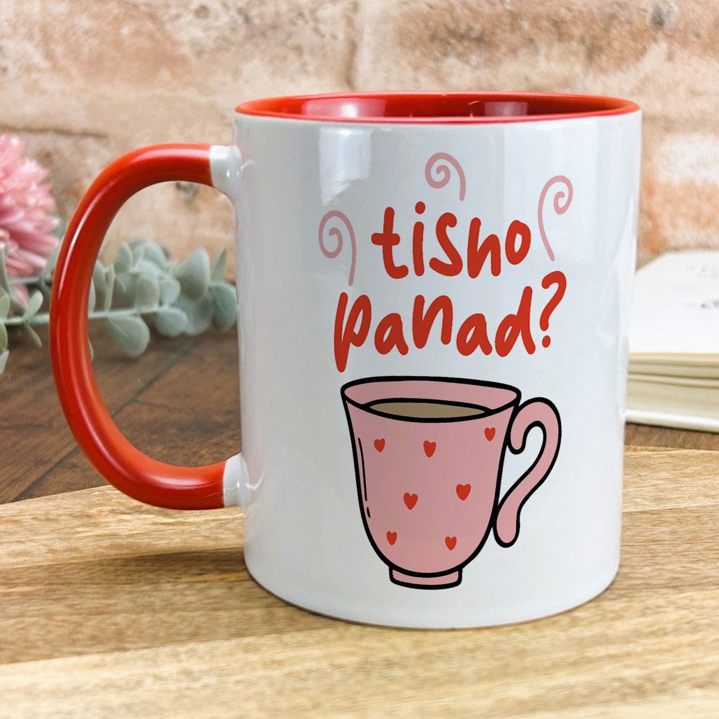 a red and white coffee mug sitting on top of a wooden table