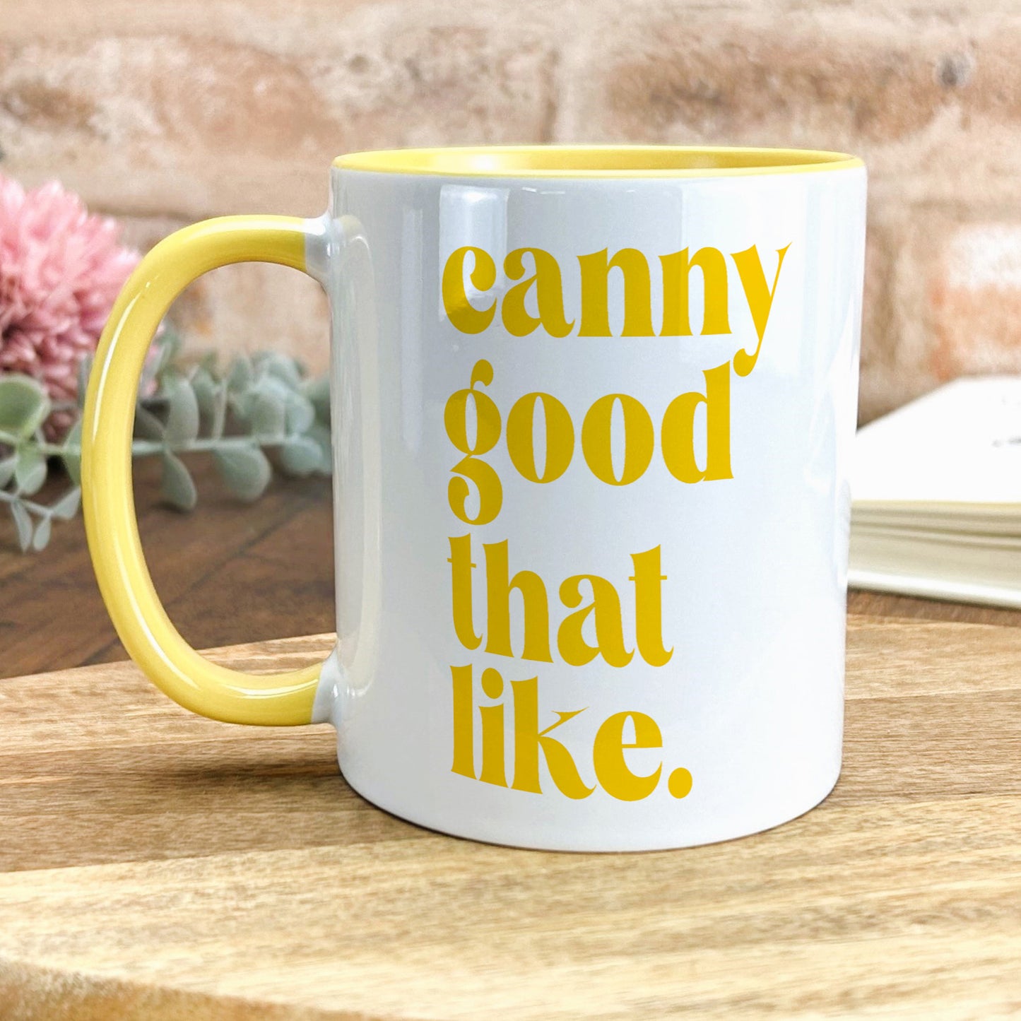 a yellow and white coffee mug sitting on top of a wooden table