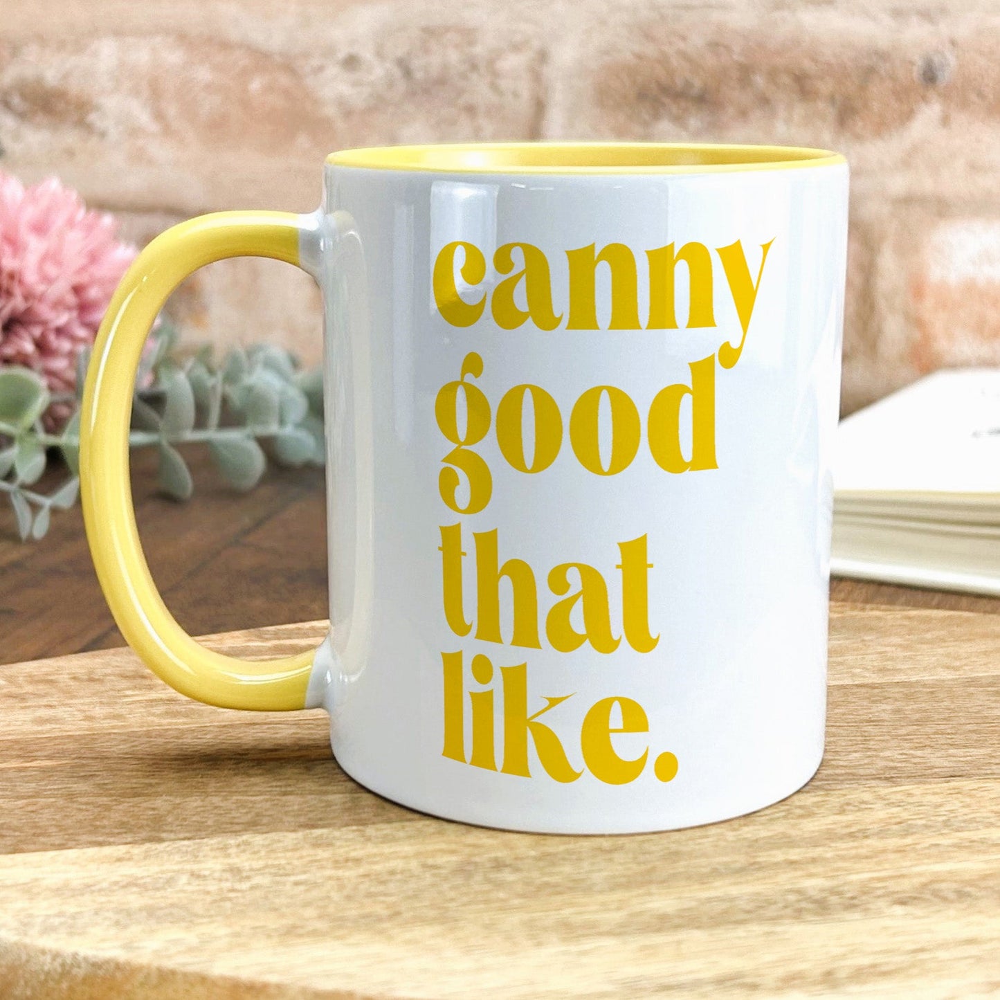 a yellow and white coffee mug sitting on top of a wooden table