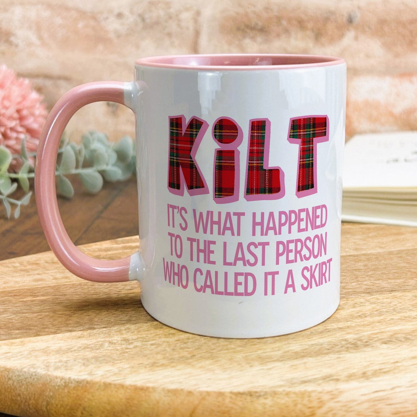 a pink and white coffee mug sitting on top of a wooden table
