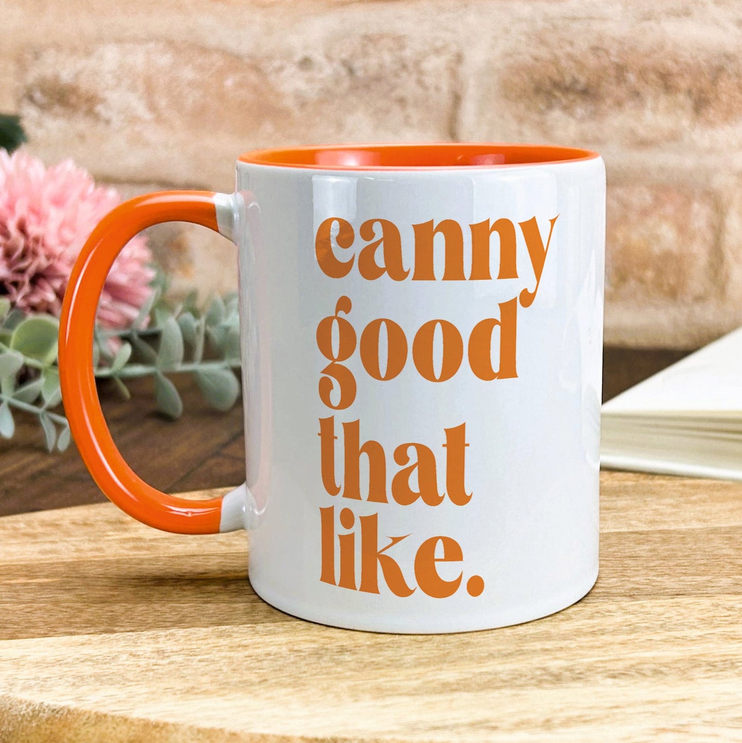 a white and orange coffee mug sitting on top of a wooden table