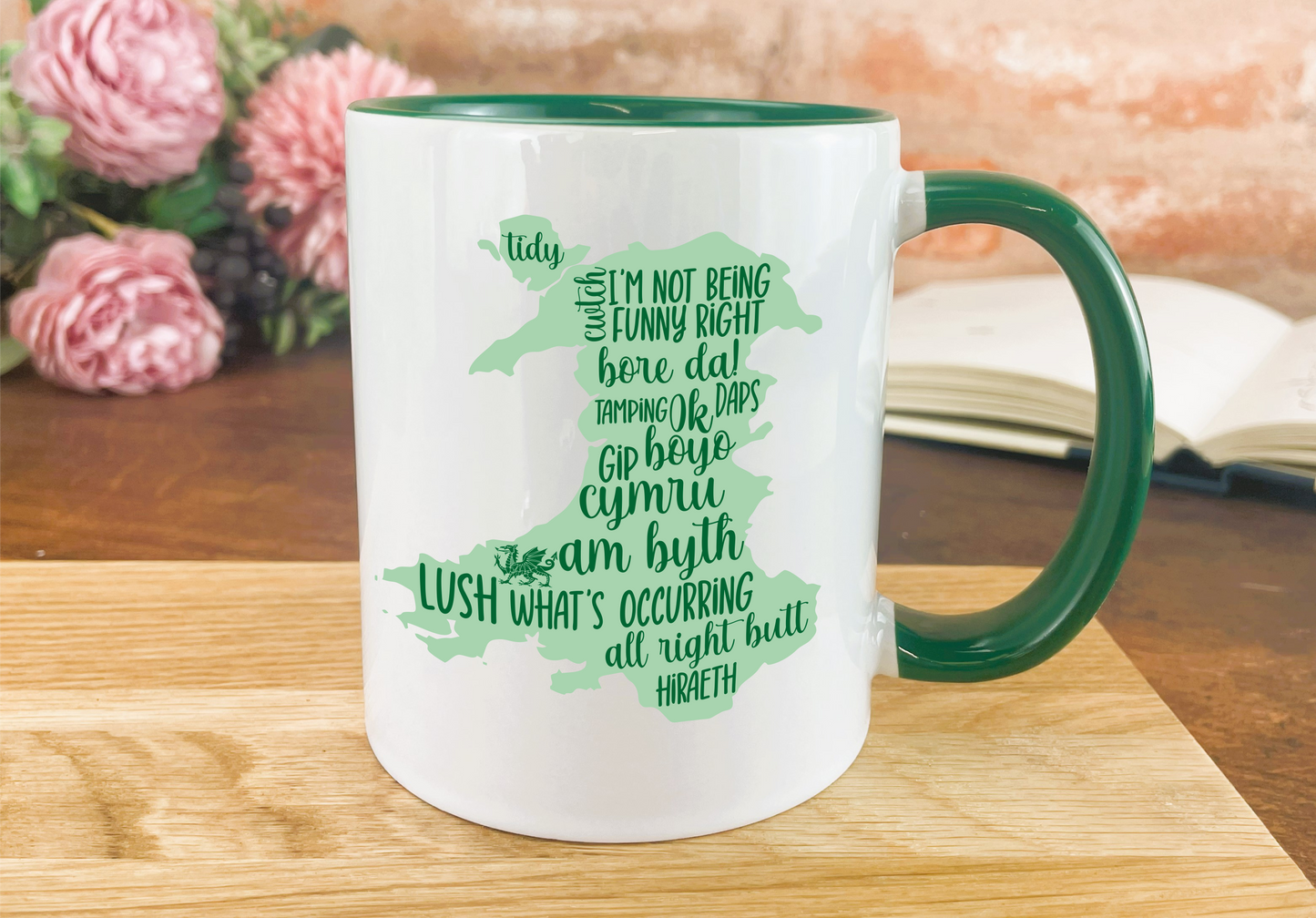 a green and white coffee mug sitting on top of a wooden table