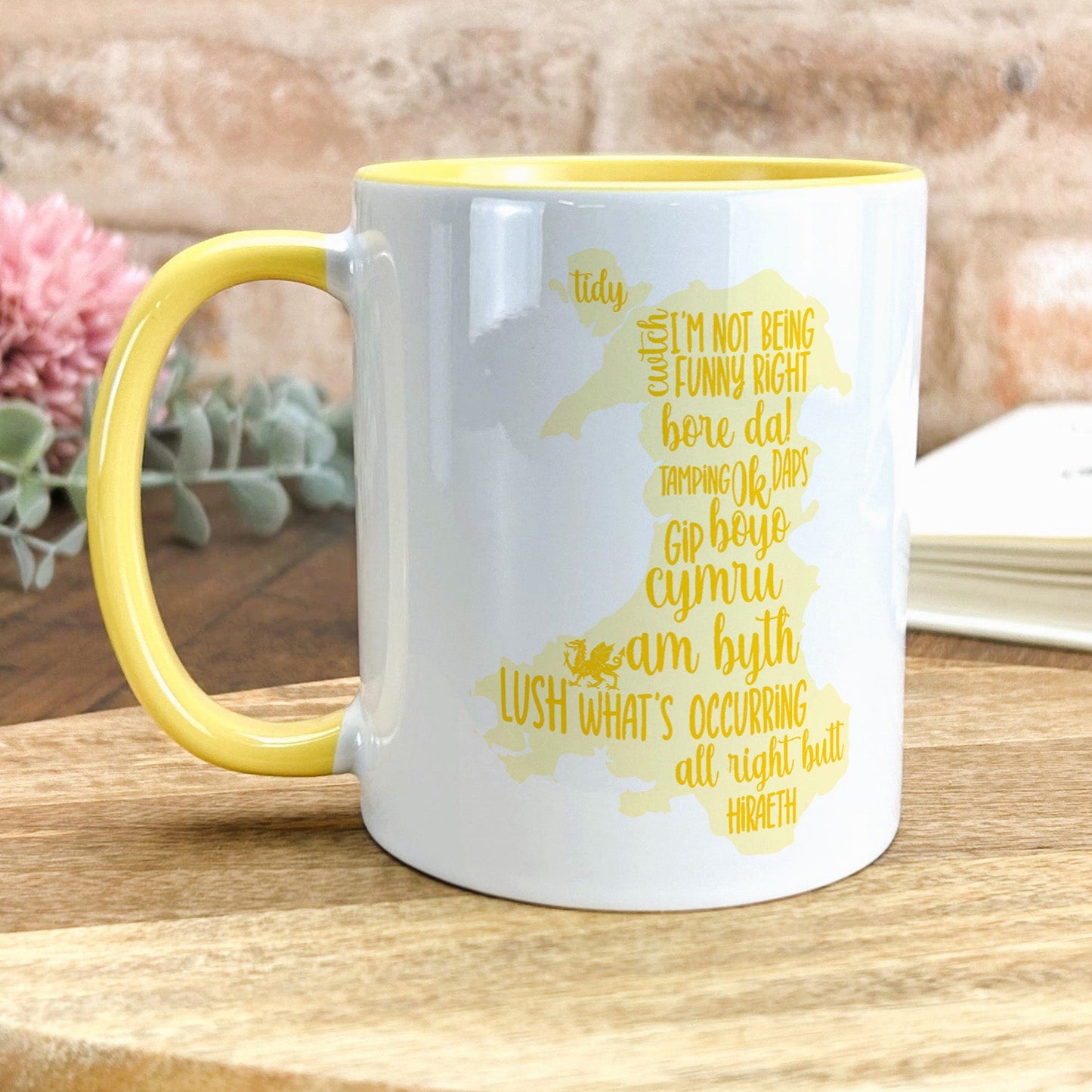 a yellow and white coffee mug sitting on top of a wooden table