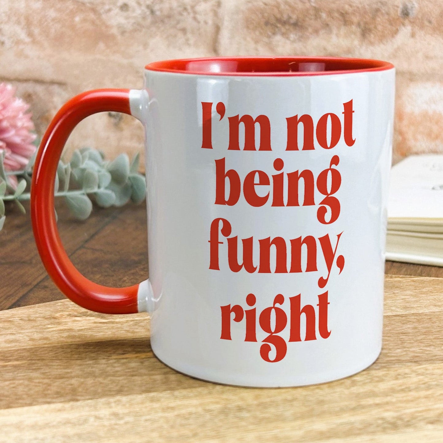 a red and white coffee mug sitting on top of a wooden table