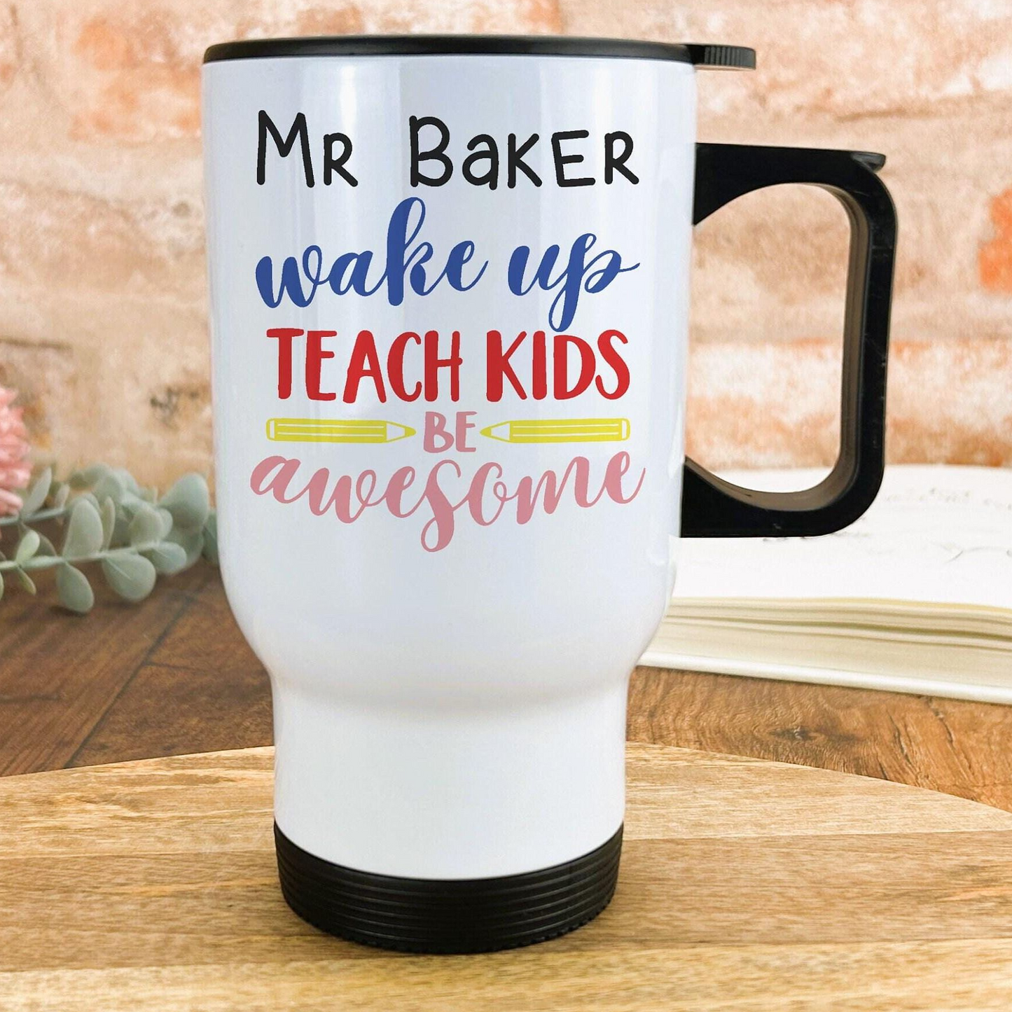 A white travel mug with text printed on it, placed on a wooden surface.