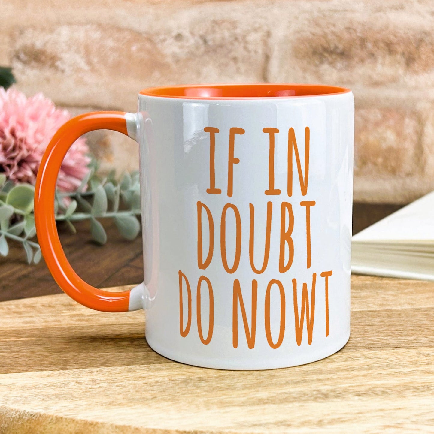 a white and orange coffee mug sitting on top of a wooden table