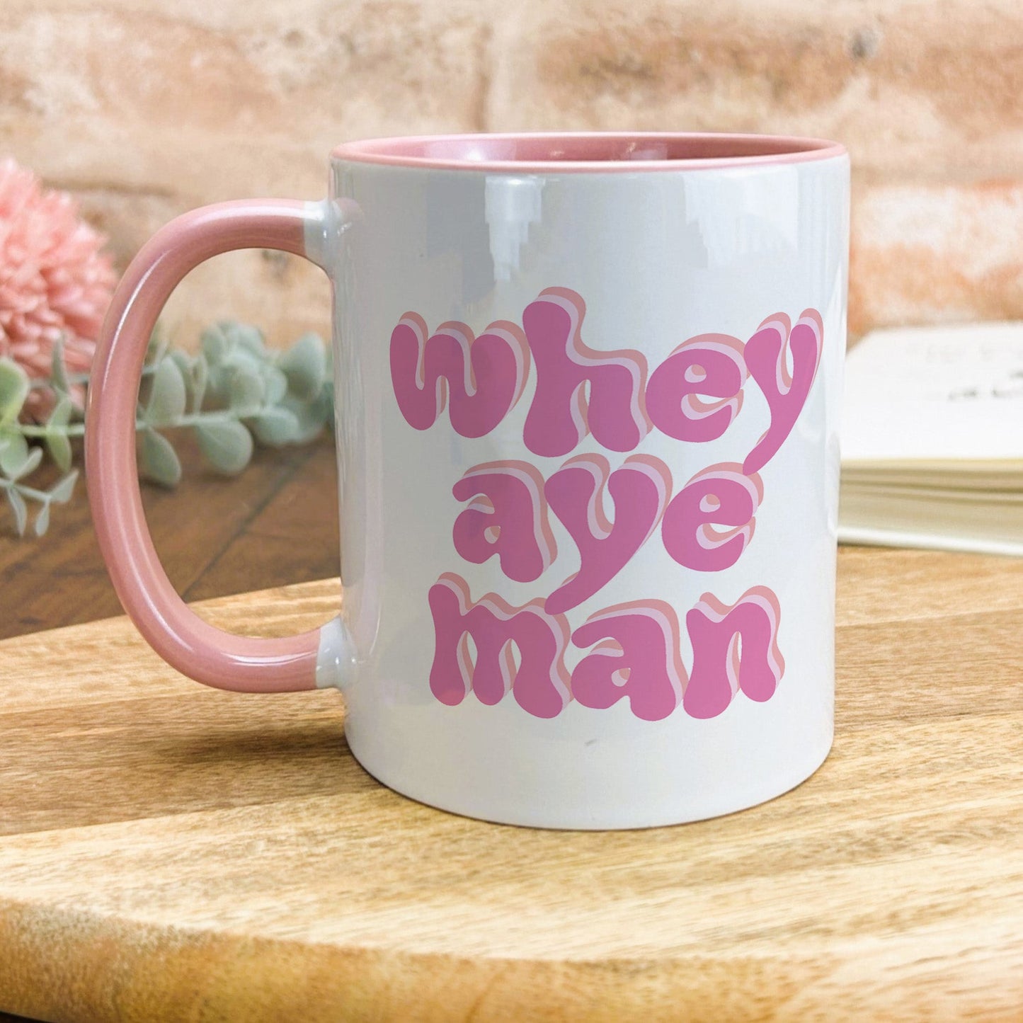 a pink and white coffee mug sitting on top of a wooden table