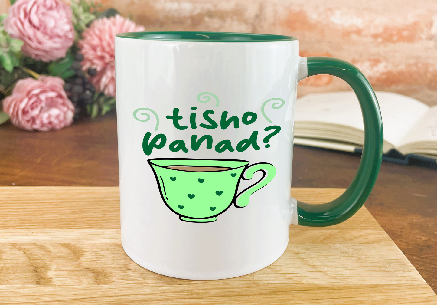 a green and white coffee mug sitting on top of a wooden table