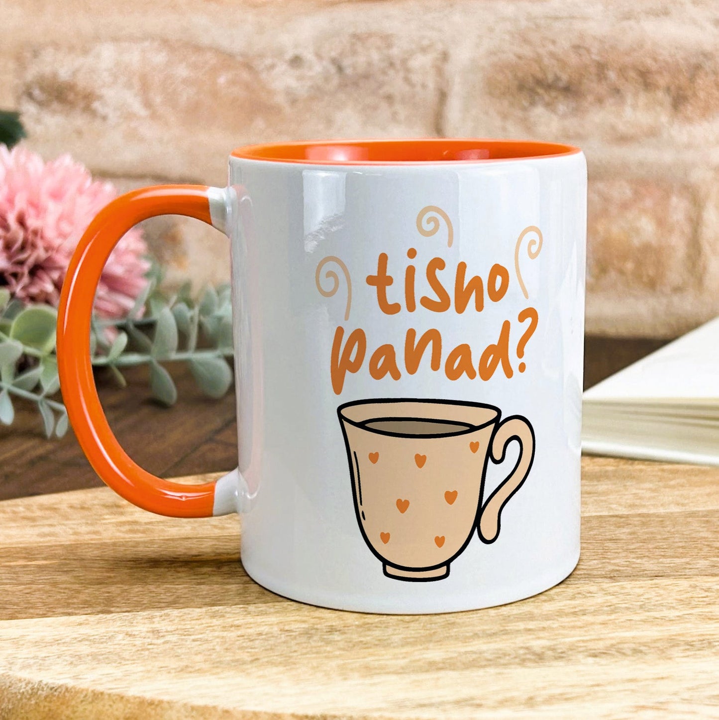 a white and orange coffee mug sitting on top of a wooden table