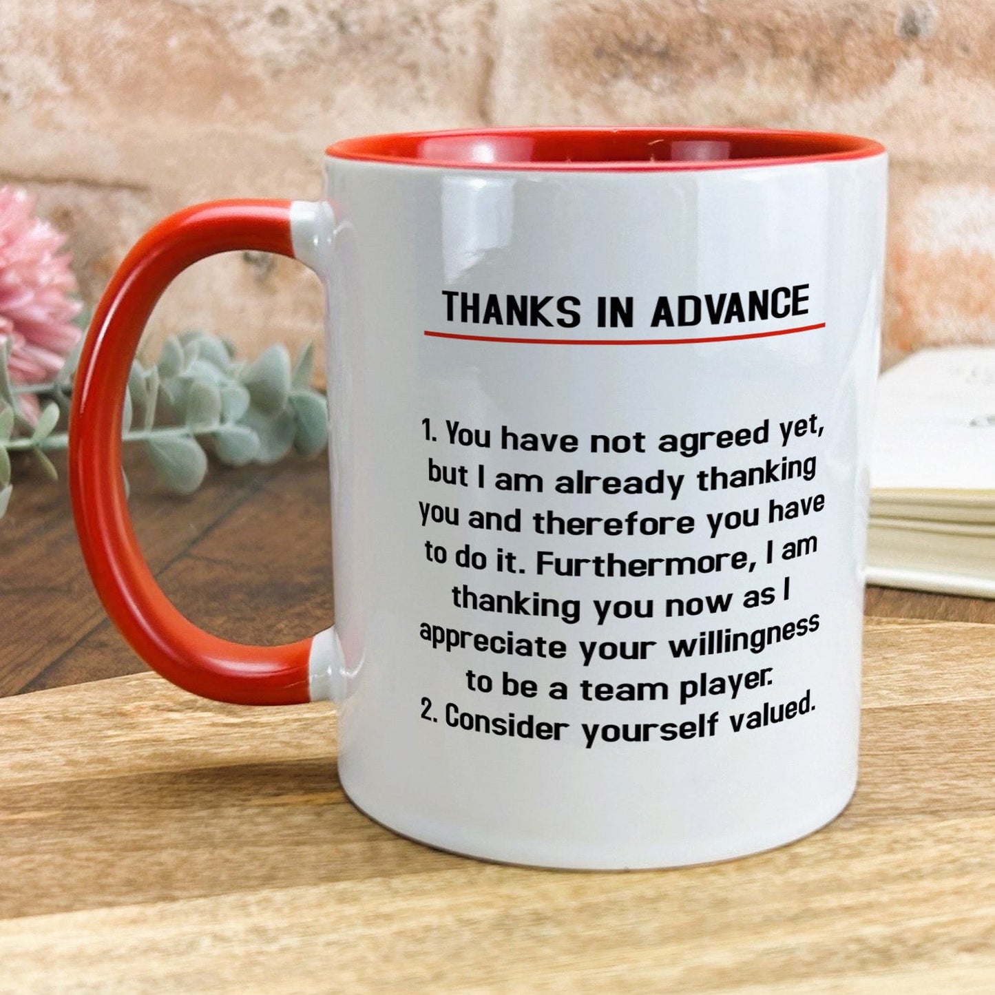 a red and white coffee mug sitting on top of a wooden table