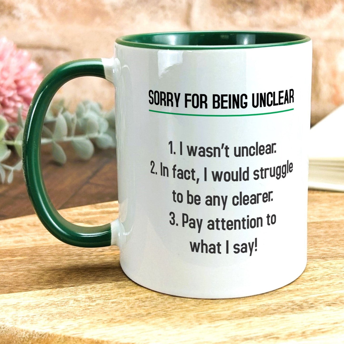 a green and white coffee mug sitting on top of a wooden table