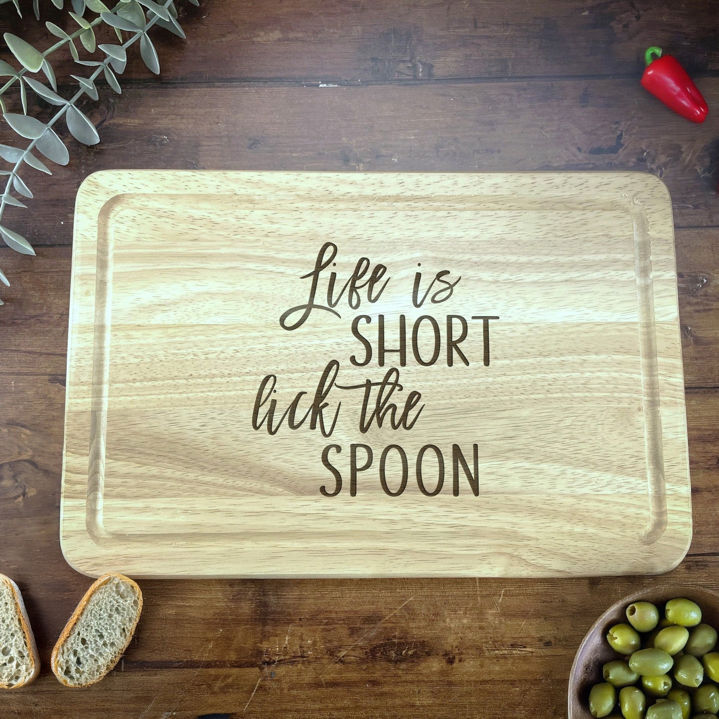 a wooden cutting board that says life is short but the spoon