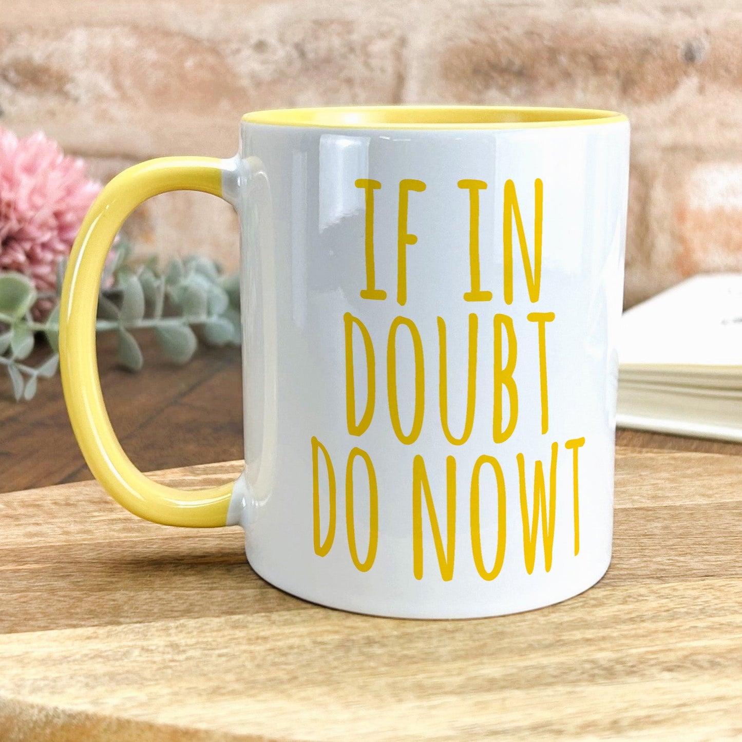 a yellow and white coffee mug sitting on top of a wooden table