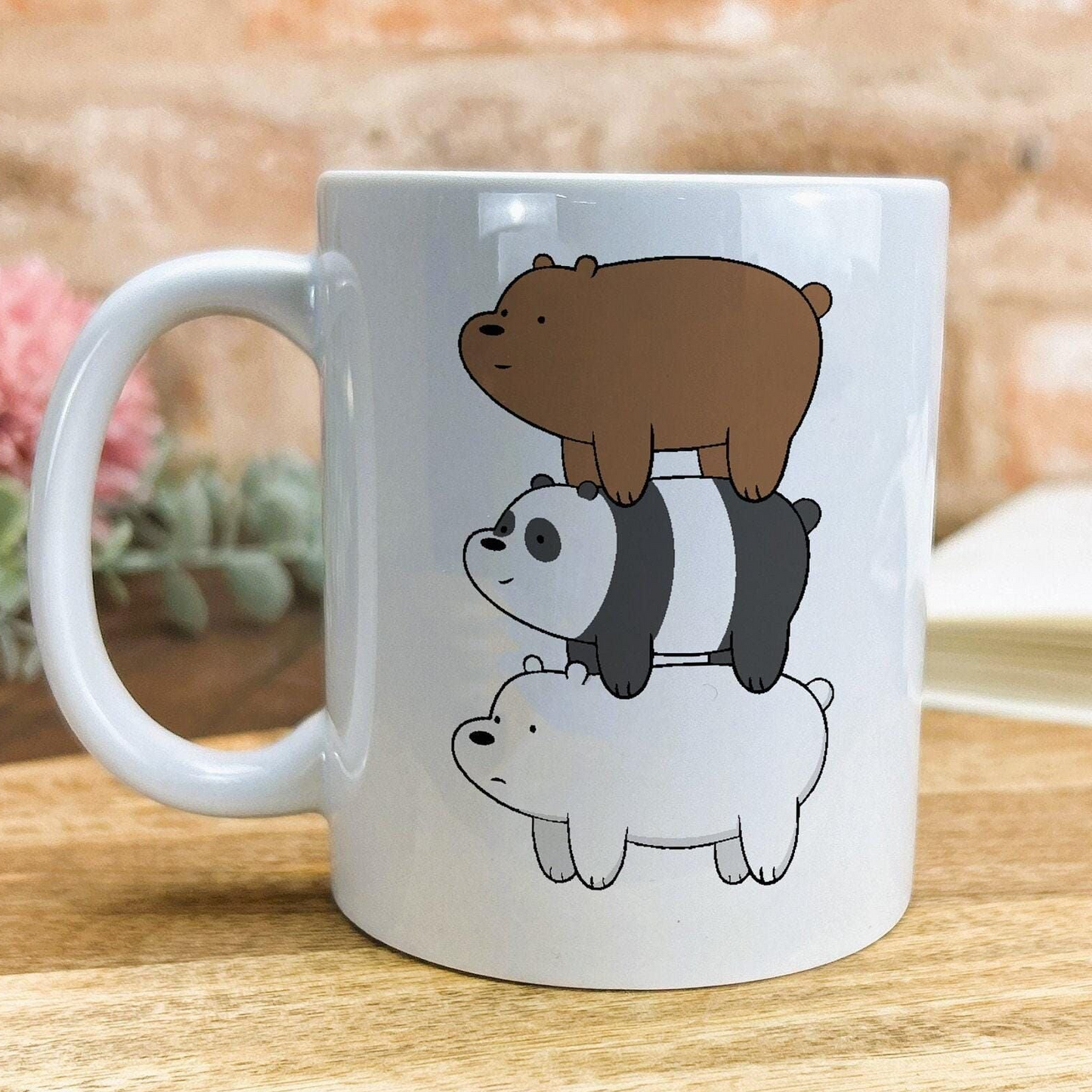 A white ceramic mug with a design featuring three cartoon polar bears stacked on top of each other.