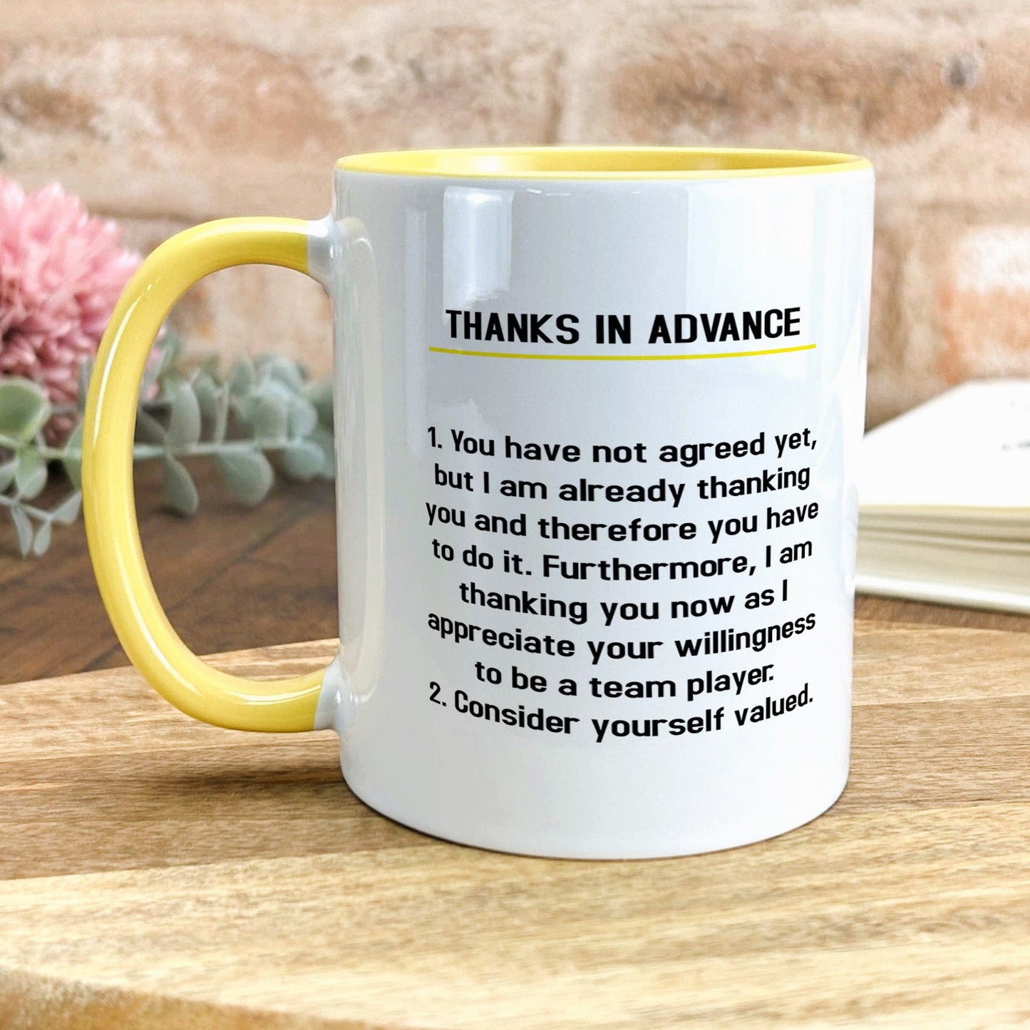 a yellow and white coffee mug sitting on top of a wooden table