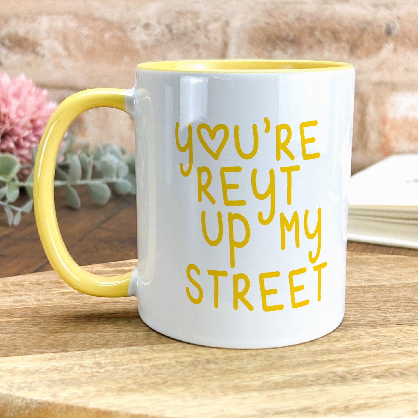 a yellow and white coffee mug sitting on top of a wooden table