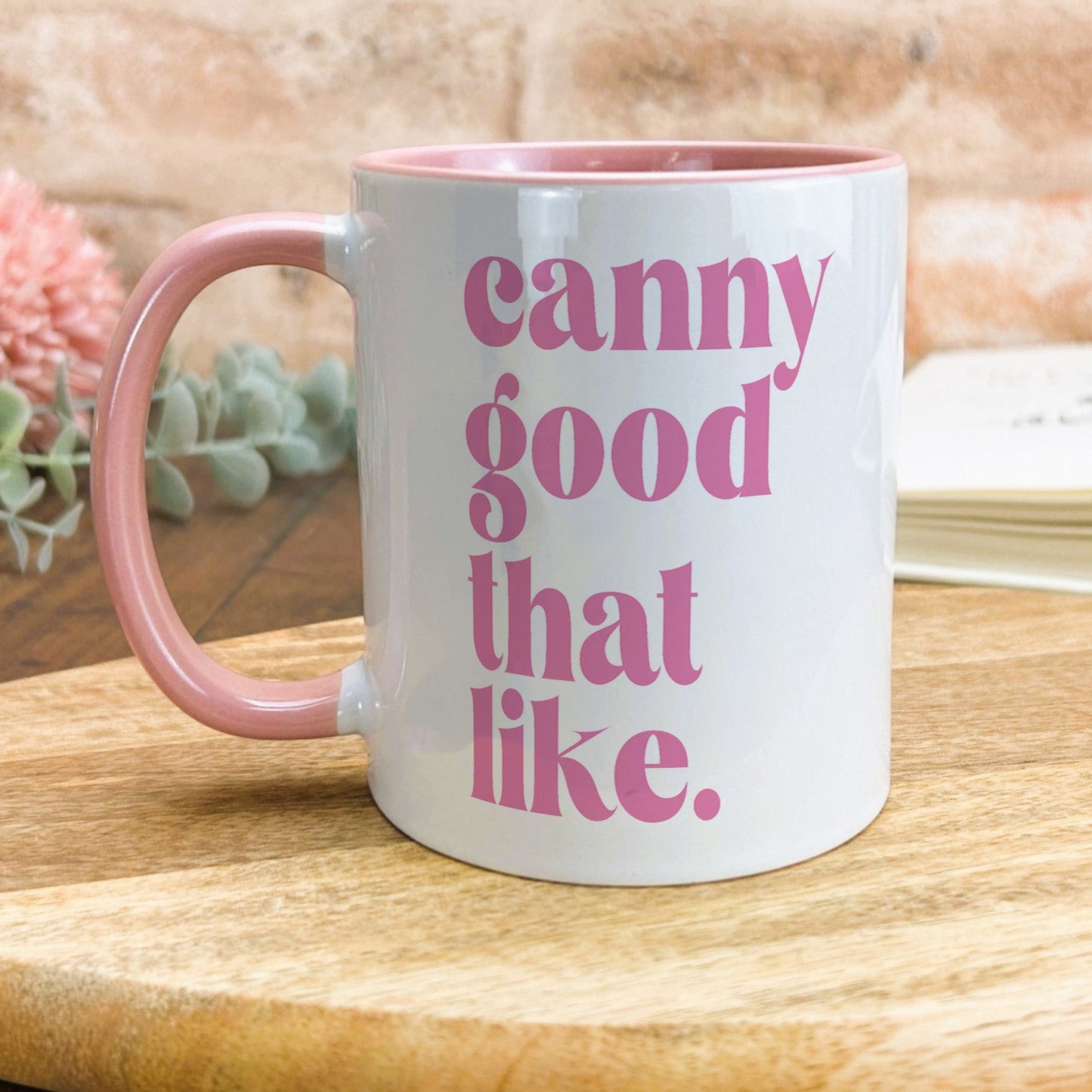 a pink and white coffee mug sitting on top of a wooden table