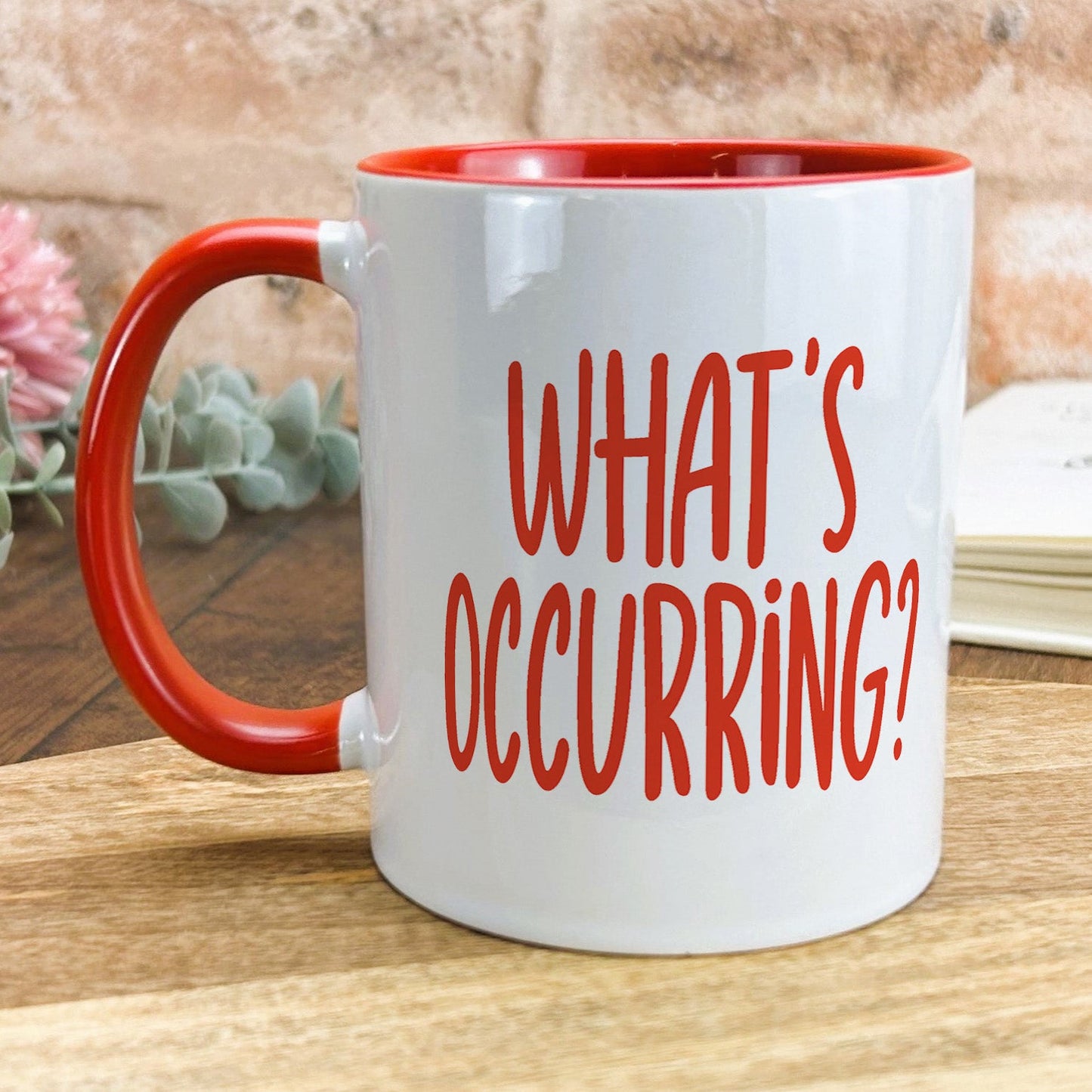 a red and white coffee mug sitting on top of a wooden table