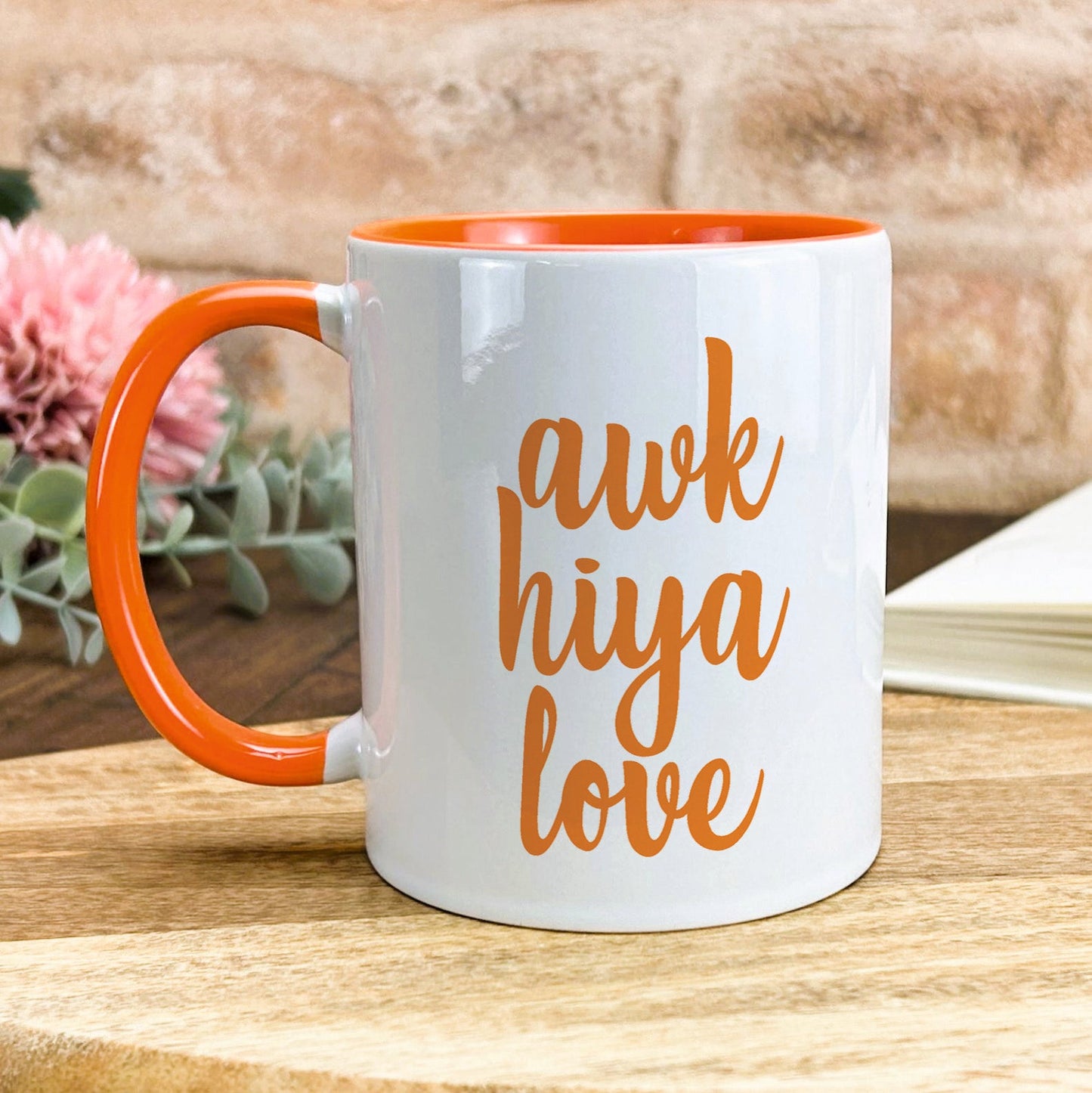 a white and orange coffee mug sitting on top of a wooden table