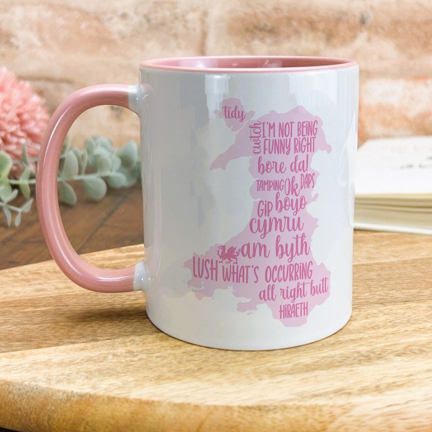 a pink and white coffee mug sitting on top of a wooden table
