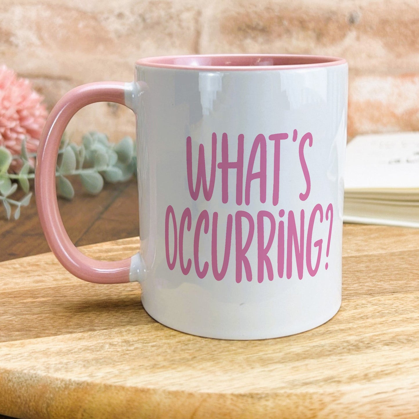 a pink and white coffee mug sitting on top of a wooden table