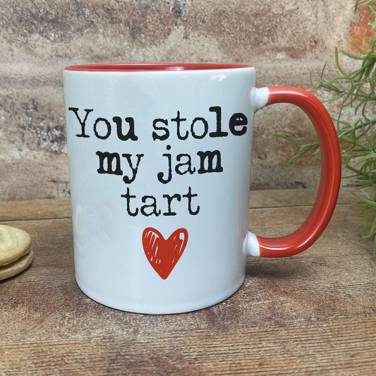A white mug with a red handle, featuring a humorous text that reads "You stole my jam tart" along with a red heart symbol.