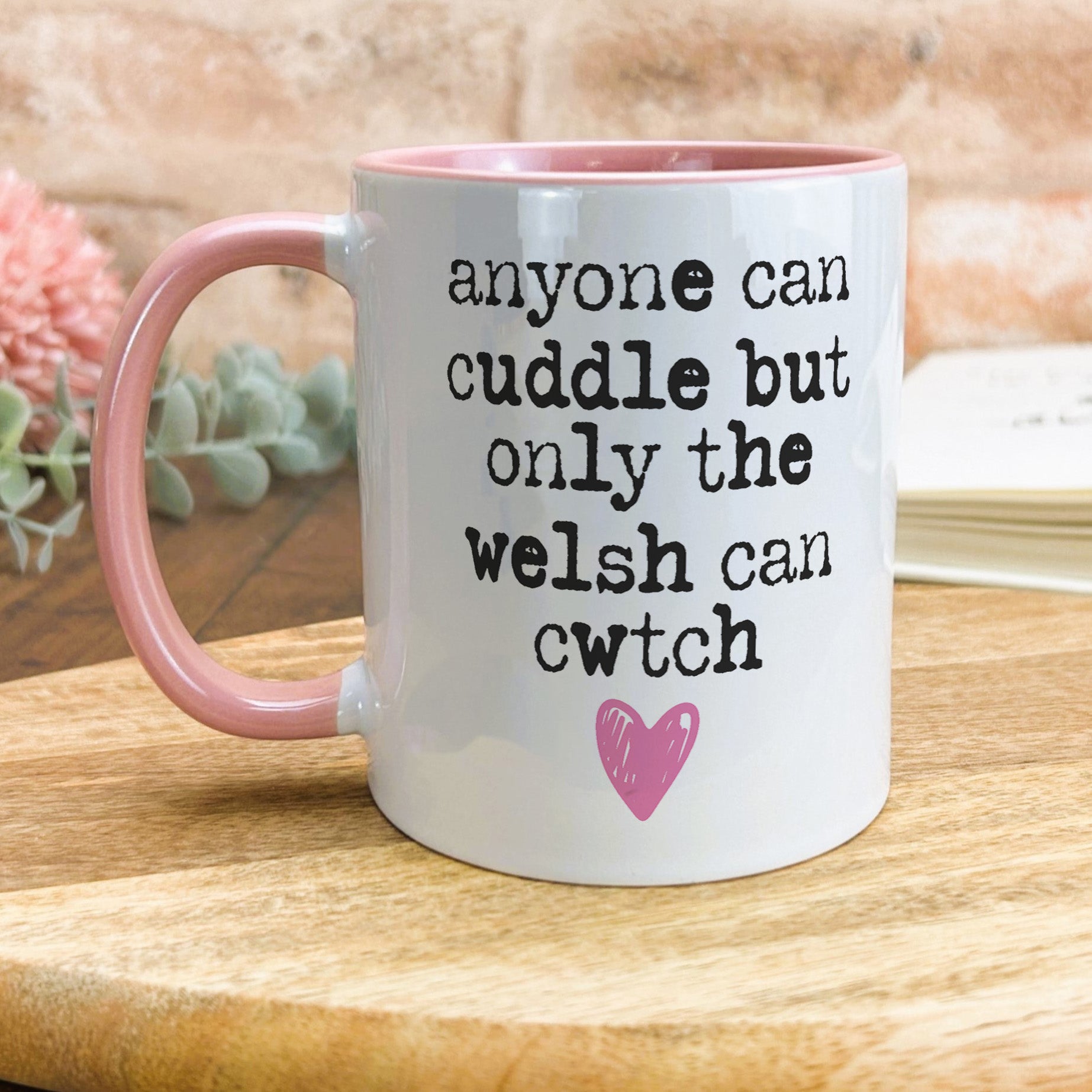 a pink and white coffee mug sitting on top of a wooden table