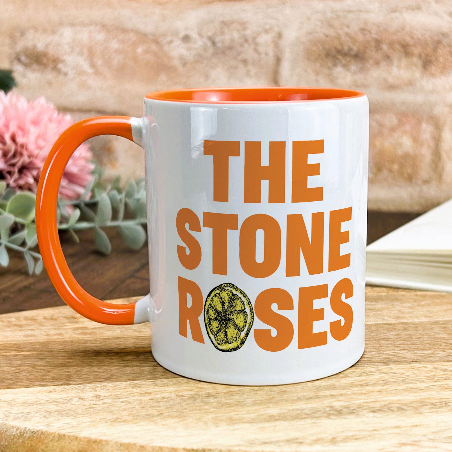 a white and orange coffee mug with the stone roses on it