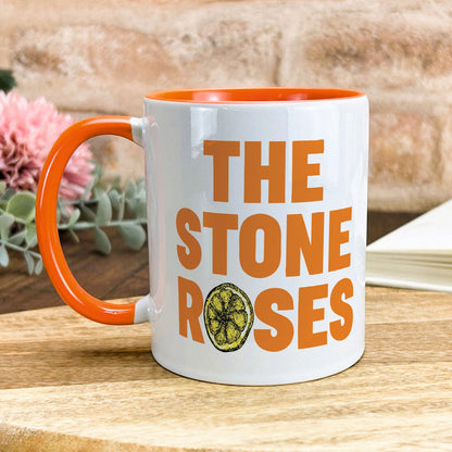 a white and orange coffee mug with the stone roses on it