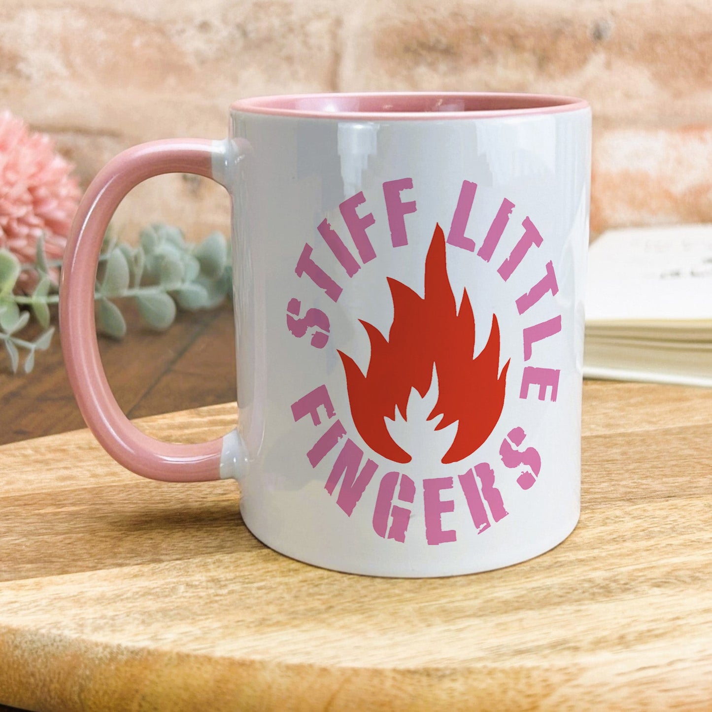 a pink and white coffee mug sitting on top of a wooden table