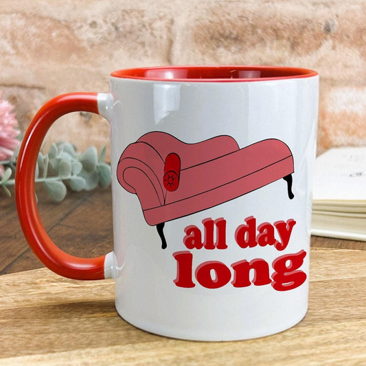 A white mug with a red handle, featuring a cartoon image of a red sofa and the text "all day long" printed on it.