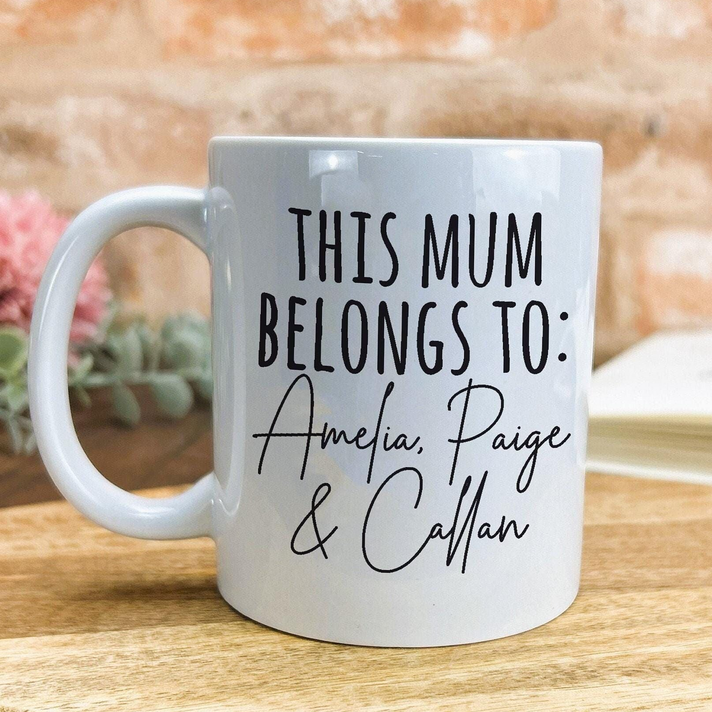 A white ceramic mug with black text printed on it, placed on a wooden surface.