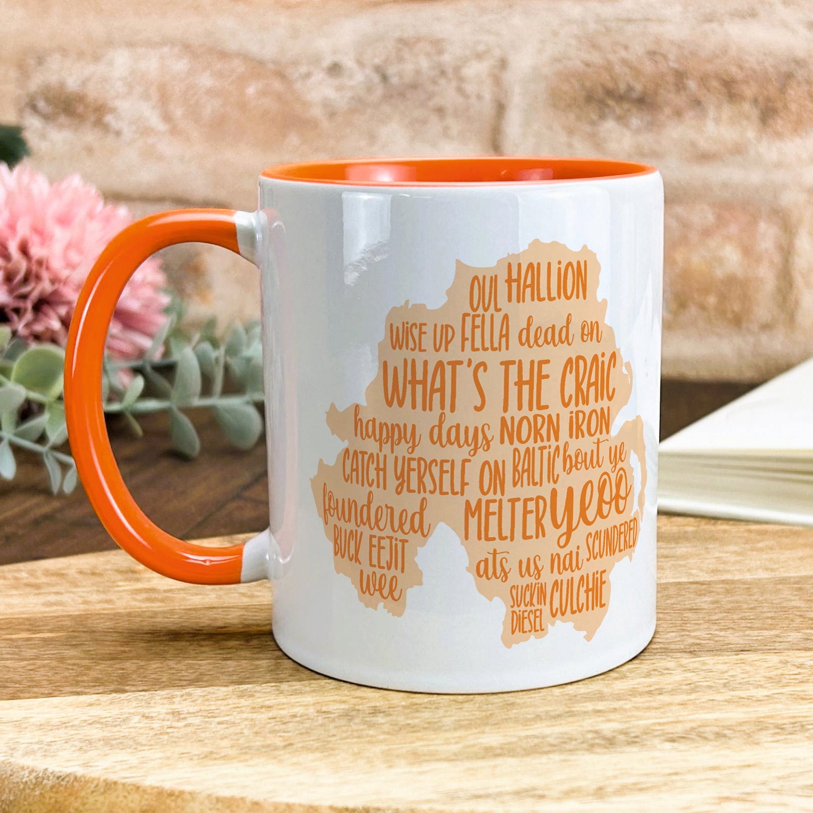 a white and orange coffee mug sitting on top of a wooden table
